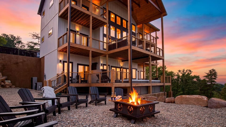 Gather around the fire pit as the multi-level mountain retreat glows beneath a colorful sunset sky.