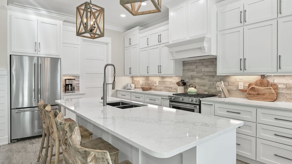 Chef’s kitchen featuring white cabinetry, a large island, and subway tile backsplash.