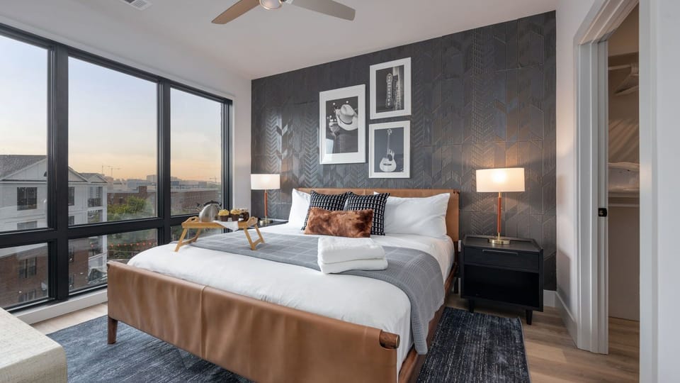 Spacious primary bedroom with a designer accent wall and large floor-to-ceiling windows.