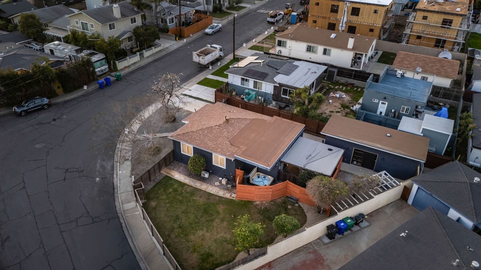 High-angle aerial shot showing the property's corner lot and surrounding residential neighborhood.