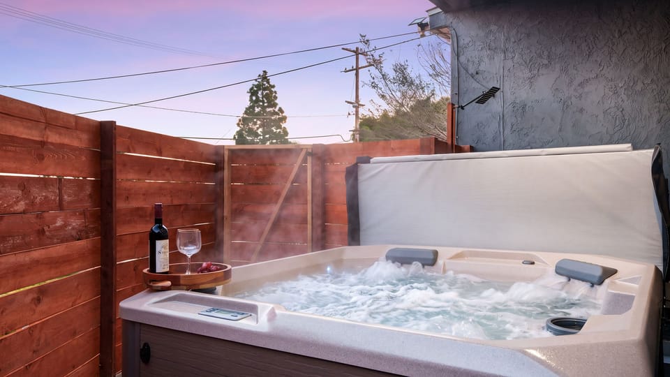 Unwind in the private hot tub tucked behind a privacy fence beneath the evening sky.