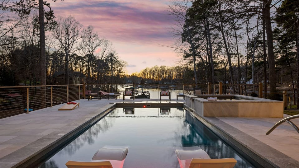 Infinity-edge pool overlooking the lake with sunset sky reflections.