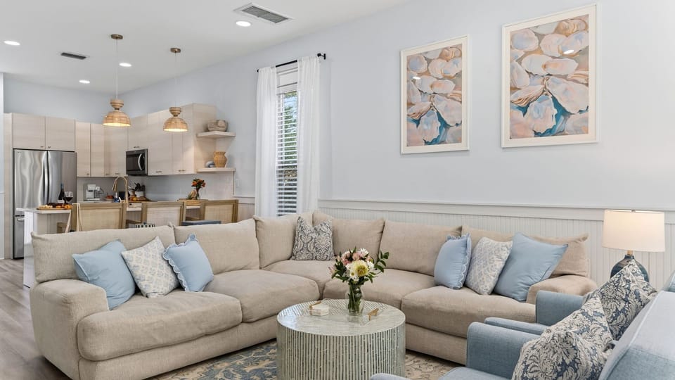 Spacious sectional sofa with blue accent pillows and coastal wall art.