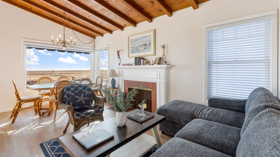 Sunlit first-floor living room with exposed wood ceilings and ocean views.