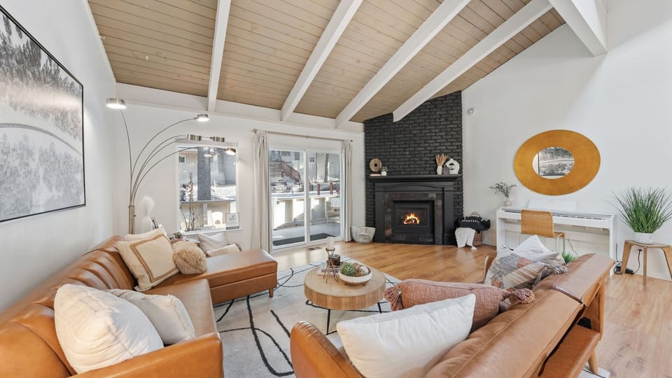 Bright living room with exposed beam, large sectional sofa, and a fireplace.
