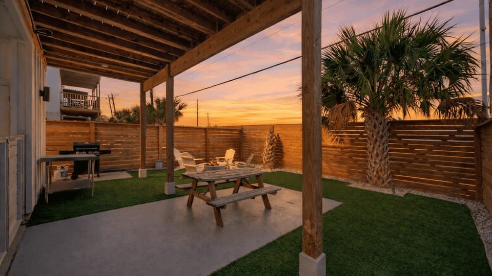 Shaded outdoor dining area with grill and fenced yard for easy cookouts.