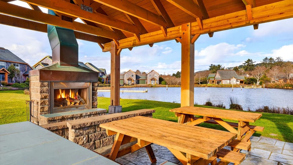 Covered lakeside pavilion with picnic tables and a cozy outdoor fireplace.