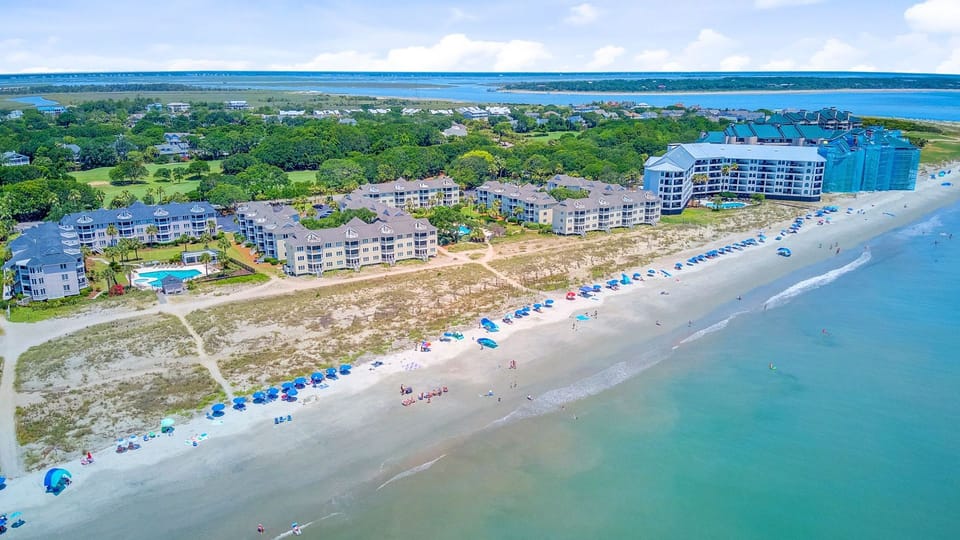 Distant aerial shot highlighting the length of the beach and the blue ocean water.