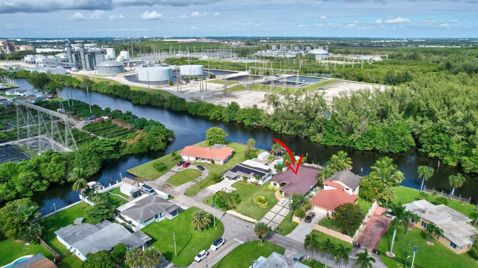 Aerial view of the waterfront home with resort-style pool, and lush tropical surroundings.