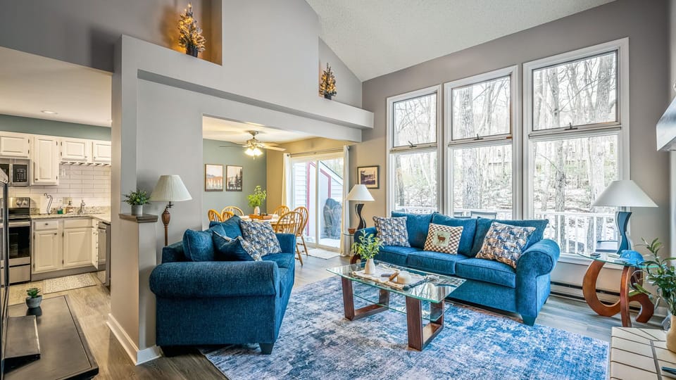 A bright, open living space with vaulted ceilings, forest views, and cozy seating—perfect for gathering after a day in the Poconos.