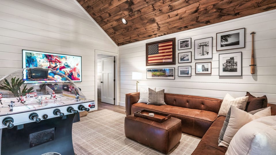 Dedicated game room with arcade-style bubble hockey, plush seating, and a cozy lounge setup for all-ages fun.
