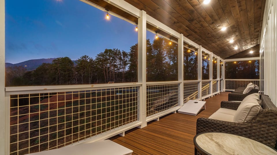 The expansive upper deck is set for evening fun with cornhole, cushioned seating, and warm string lights.