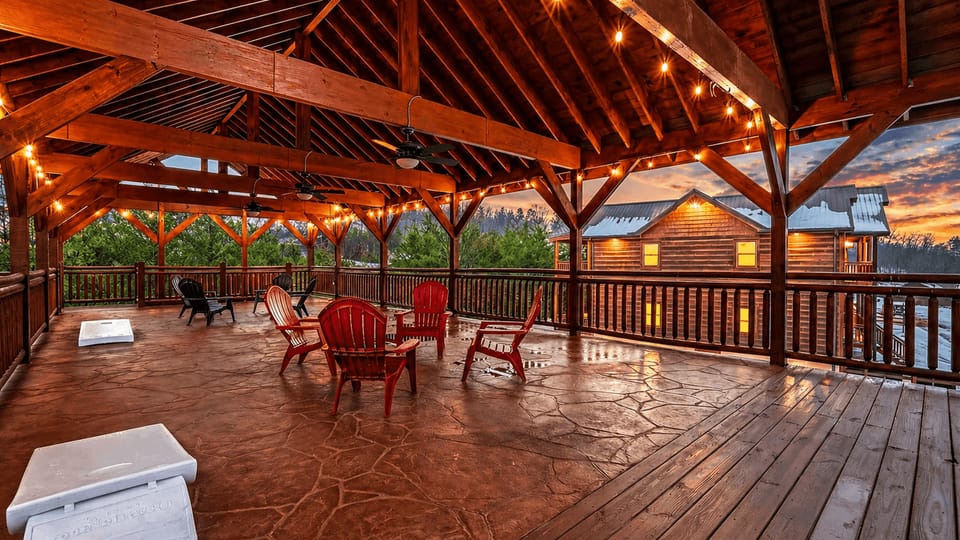 Expansive covered pavilion with string lights, ceiling fans, and ample seating—an inviting space for evening gatherings, games, and mountain air views.