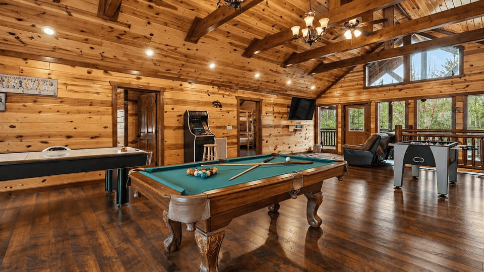 Spacious game loft with vaulted wood ceilings, air hockey, pool table, arcade games, and a built-in putting green for friendly competitions and laid-back fun.