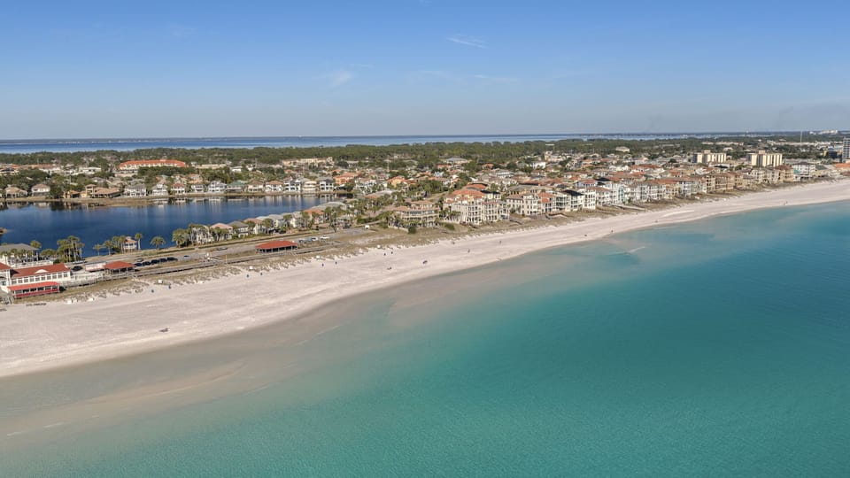 Sweeping aerial view of the emerald coastline and sugar-white sand beaches just minutes away—your gateway to classic Destin beach days and sunset strolls.