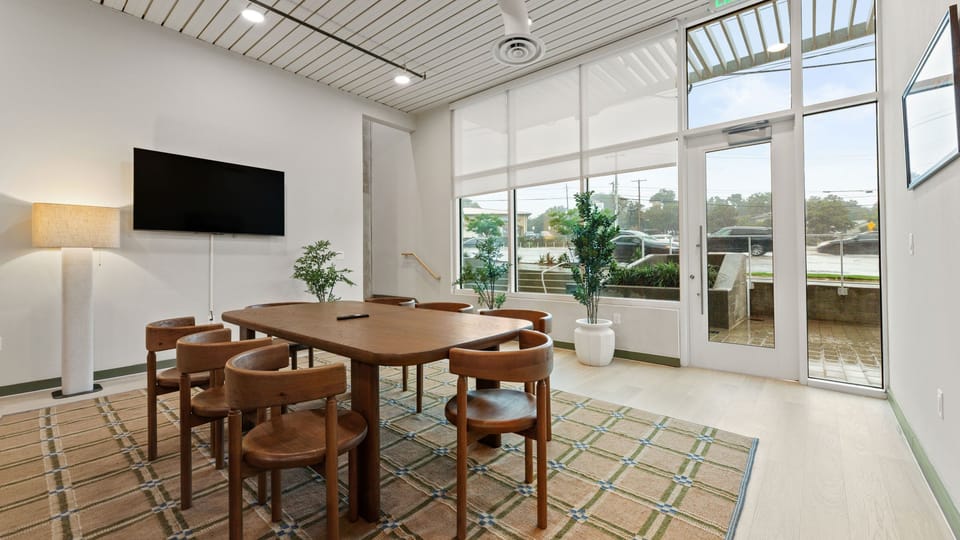 A formal dining space with a large wooden table set against floor-to-ceiling windows.