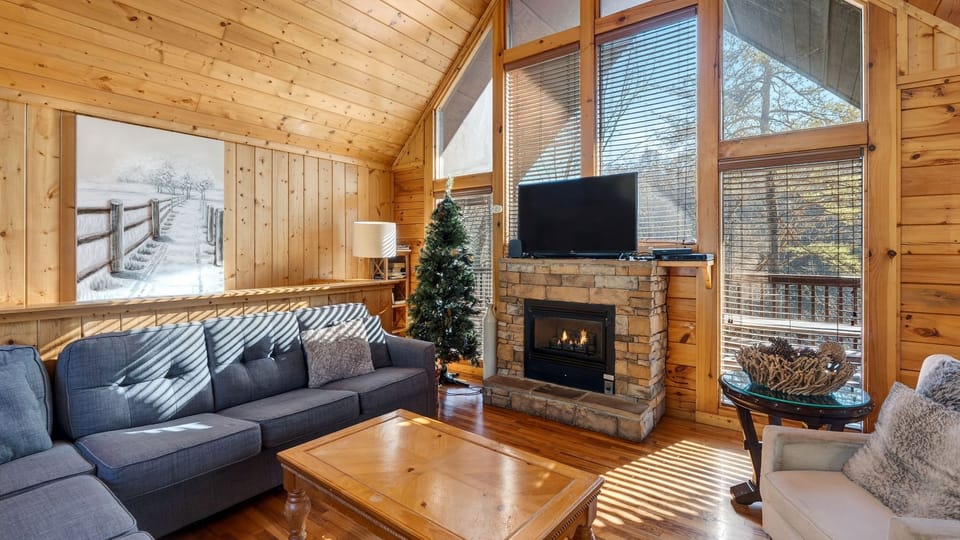 Living area featuring a large window, TV, sectional sofa, and a fireplace.