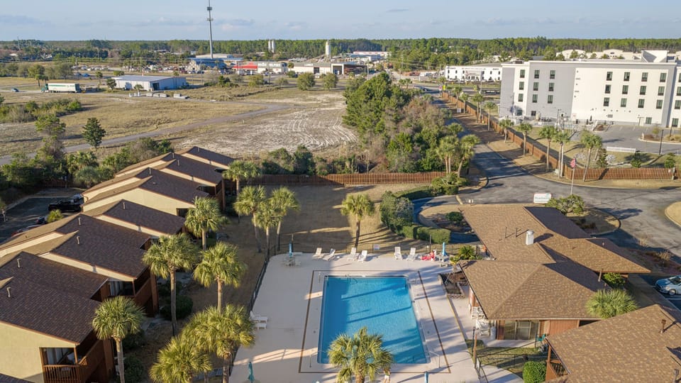 Overhead view of the fenced-in community swimming pool surrounded by palm trees.