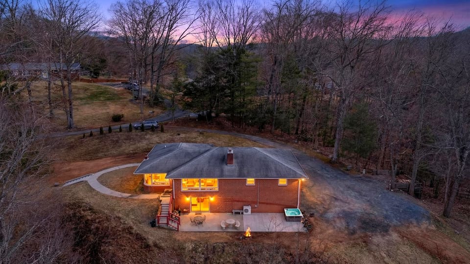 Twilight aerial: hot tub + fire pit, tucked into a quiet wooded retreat.