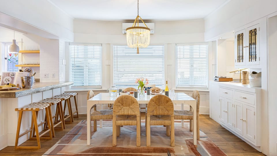 Airy, sunlit dining space with chic chandelier, breakfast bar seating, and an open flow into the kitchen.