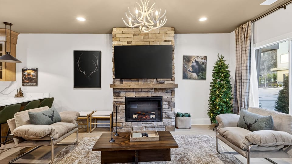 Gather by the stone fireplace—huge TV, cozy seating, and a warm lodge-style vibe.