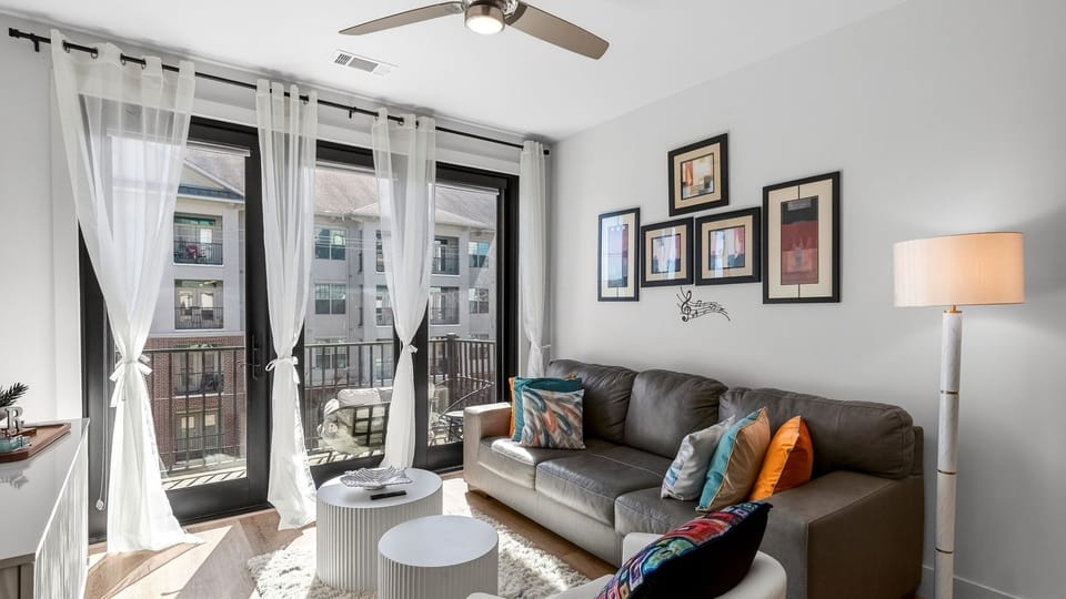 Bright, airy living room with floor-to-ceiling windows, comfy seating, and balcony access.