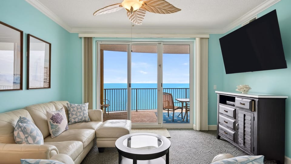Bright coastal living room with floor-to-ceiling sliders opening to your private ocean-view balcony.