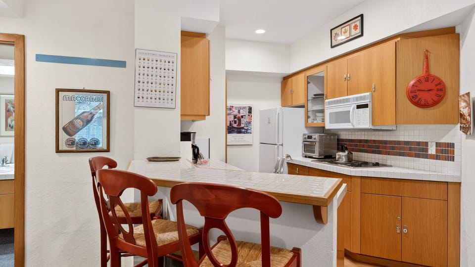 Compact, fully equipped kitchen with breakfast bar seating — perfect for morning coffee or easy après-ski meals at home.