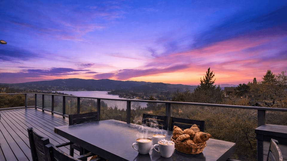Outdoor dining deck overlooking a panoramic sunset and lake view.