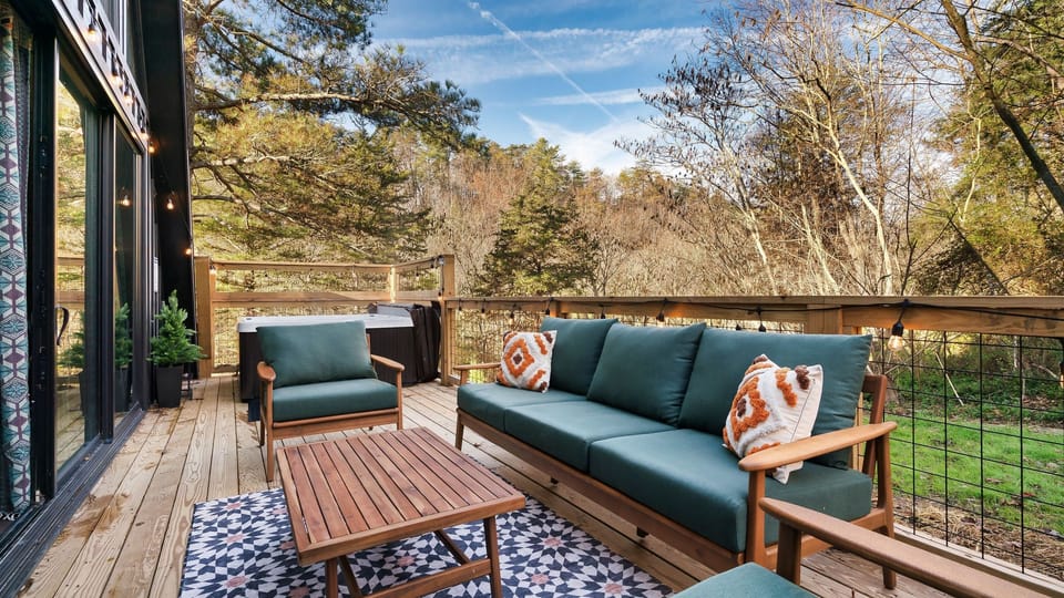 Forest-view deck with lounge seating, string lights, and a private hot tub—perfect for slow mornings and starry nights.