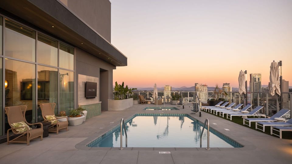 The rooftop shared pool deck transforms into an ambient oasis as the city lights come up.