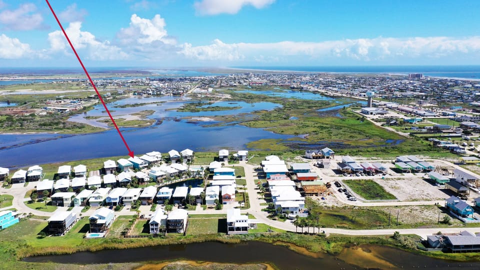 Aerial view—your coastal home is marked, just steps from the community pool with bayfront surroundings.