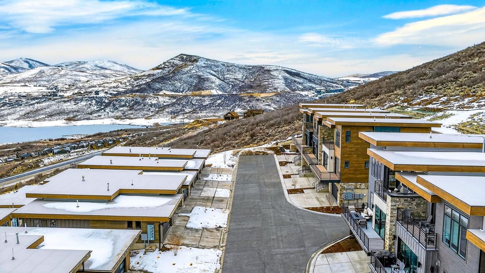 Front-row Park City scenery—snowy rooftops below with sweeping lake-and-ski-run views in the distance.