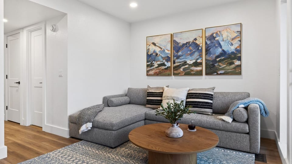 Cozy, modern living area with a plush sectional, warm wood accents, and mountain-inspired artwork—your perfect spot to unwind after a day on the slopes.