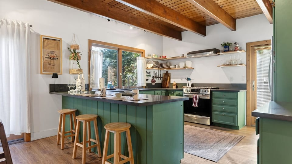 Bright, open kitchen with rustic beams, open shelving, and a cozy island—perfect for coffee and slow mountain mornings.