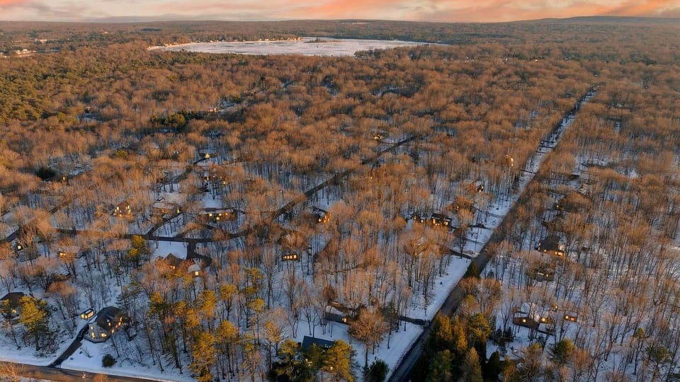 Stunning aerial drone shot of the property and surrounding forest at sunset.