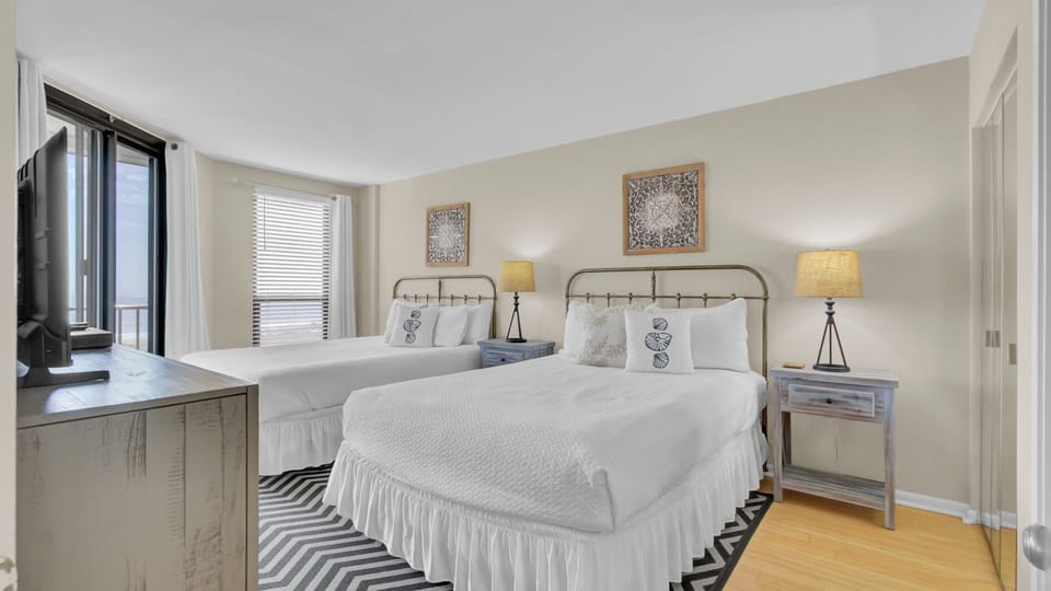 Two queen beds with white bedding and a patterned rug.
