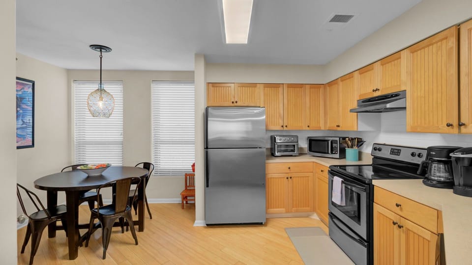 View of the stainless steel refrigerator and the transition to the dining area.