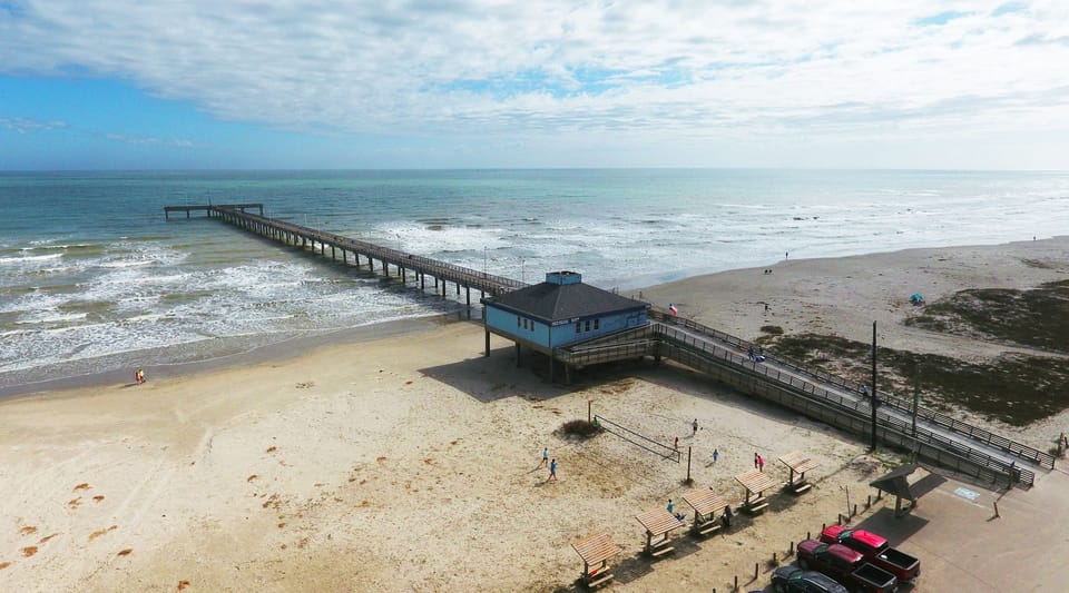 Aerial view of a long fishing pier extending into the ocean.