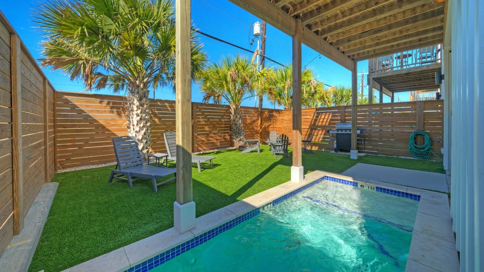 Daytime shot of the backyard featuring a small plunge pool and turf lawn. (Villa Blanca)