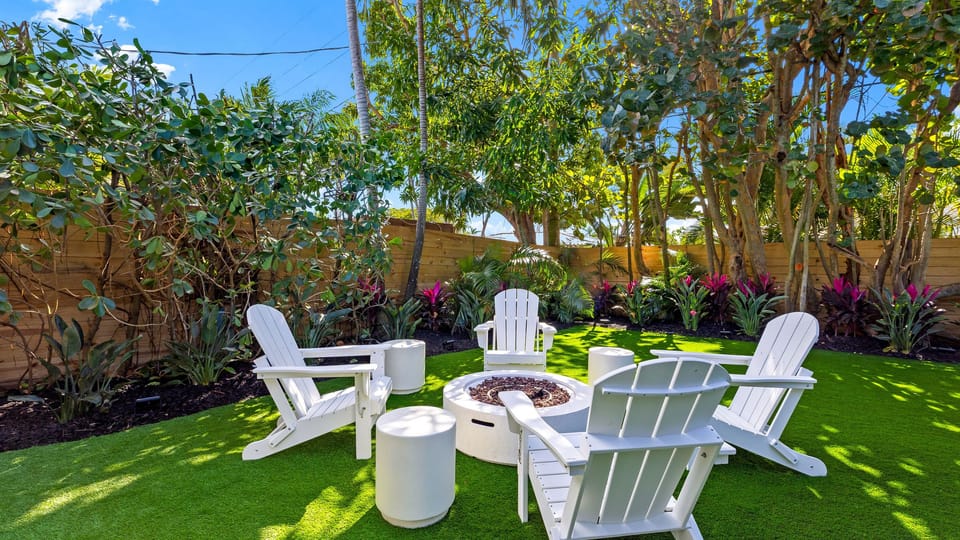 Private fire pit lounge surrounded by lush tropical landscaping.