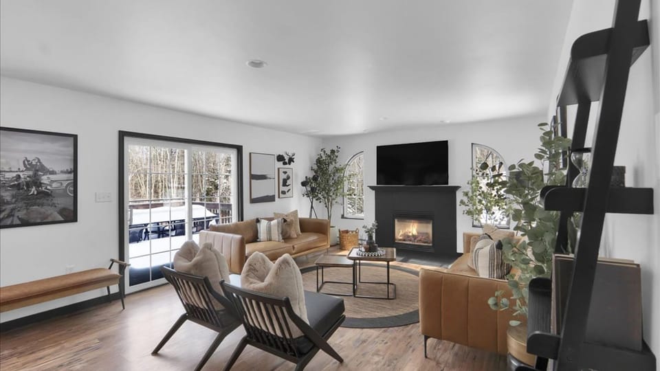 Bright great room made for gathering—fireplace glow, big-screen TV, and plenty of comfy seating for the whole crew.