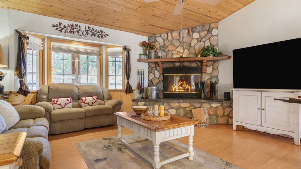 Cozy mountain living room with a stone fireplace, wood-paneled ceilings, and plenty of space to gather and unwind.