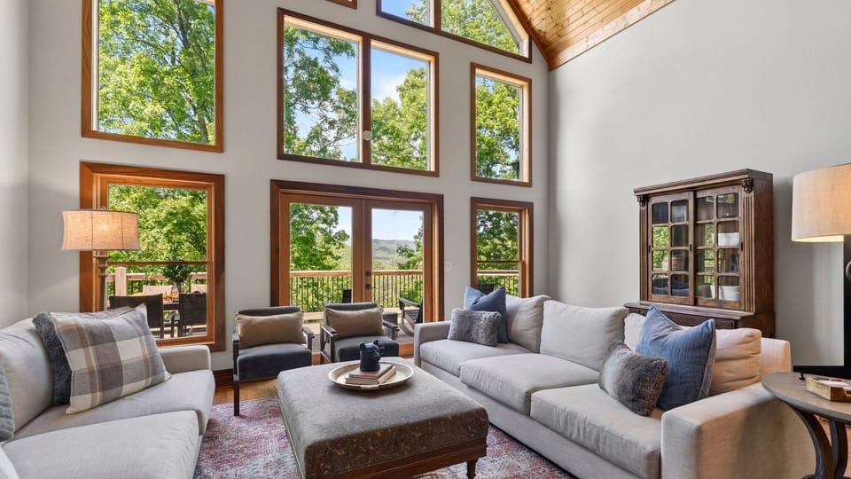 Spacious open-concept living area with soaring ceilings, stone fireplace, and seamless flow into the kitchen and loft.