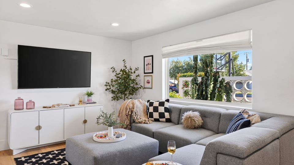 Bright, open-concept living area featuring a large grey sectional and ottoman.