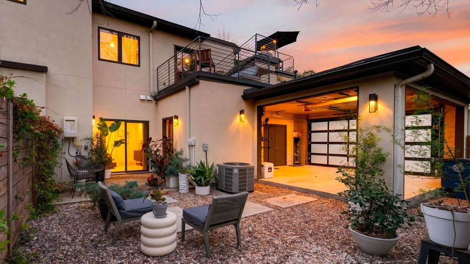 Private courtyard with cozy lounge seating and a view of the rooftop deck, glowing beautifully at sunset.