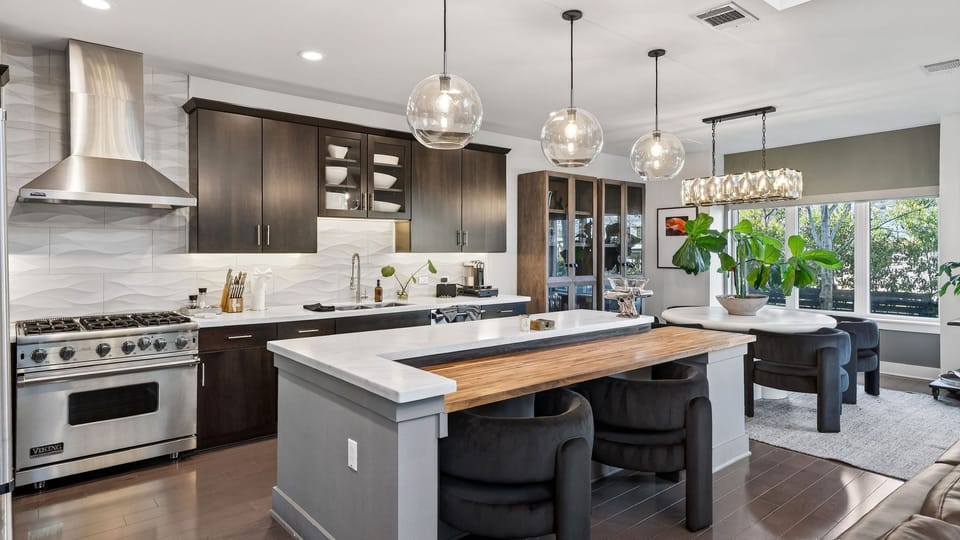 Chef’s kitchen with premium appliances, waterfall island seating, and an open layout that flows into the dining area.
