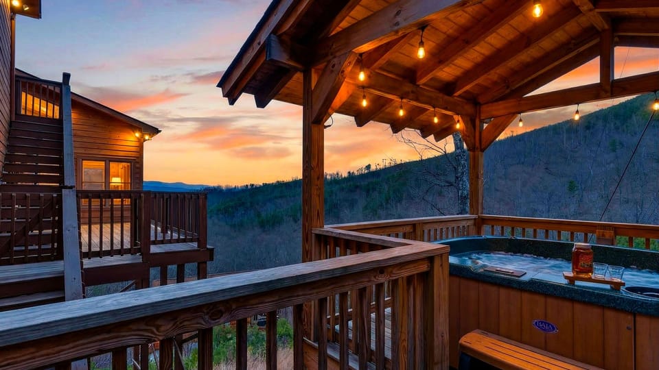 Covered deck at sunset featuring a built-in hot tub and mountain views.