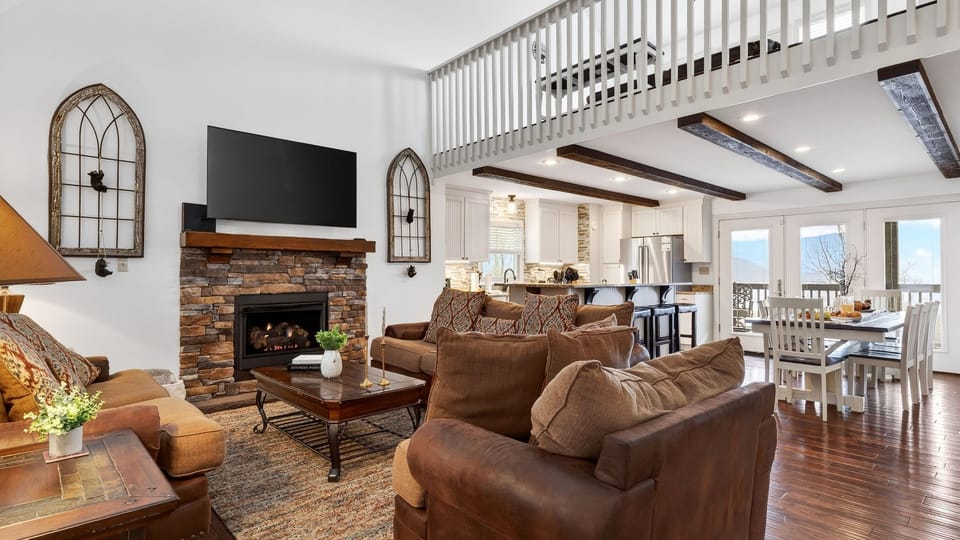 Spacious living room with a stone fireplace, leather seating, and a loft overlook.