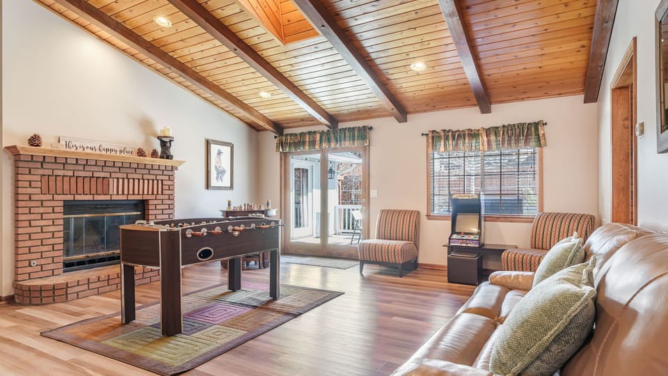 Living room with a fireplace, foosball table, and arcade machine for laid-back cabin nights.
